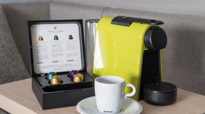 A Nespresso coffee machine, a cup, and a box with capsules and instructions.