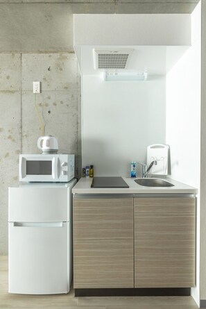 A compact kitchenette with a microwave, sink, and storage cabinets.