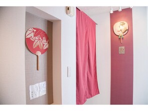 A room with a wall-mounted fan, a curtain, and a decorative item.
