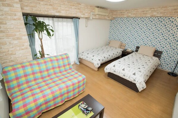 A room with two beds, a sofa, and a small table.