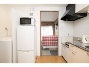 Een koelkast, een magnetron, een kookplaat, kookgerei, borden en bestek