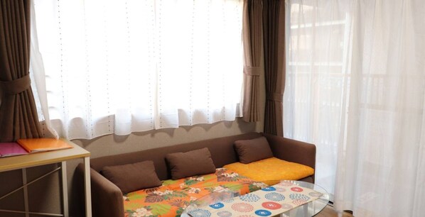 A cozy living room with a sofa, a small table, and a window with curtains.