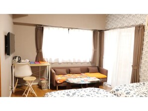 A hotel room with a sofa, a small table, a chair, and a bed.