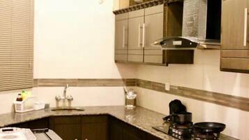 Lemari es, microwave, peralatan masak/sendok-piring, dan meja makan