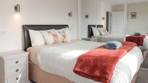 Ein Schlafzimmer mit einem großen Bett, einem Nachttisch, einer Kommode und einem Spiegel.