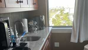 Una cocina equipada con microondas, cafetera y lavabo.