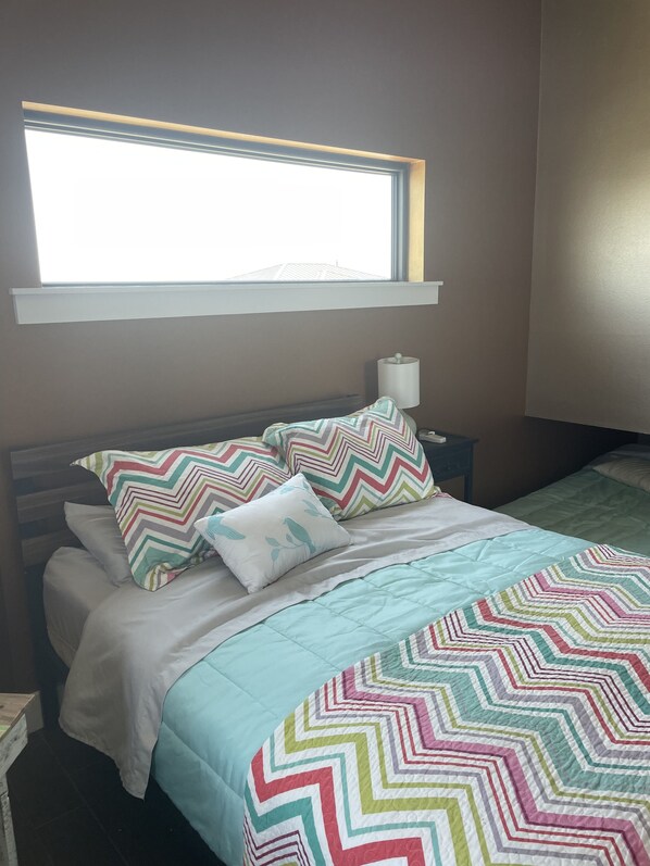 Une chambre à coucher avec un lit, des oreillers, une lampe de chevet et une fenêtre.