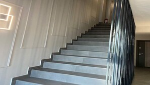 A modern staircase with a sleek design, leading to a landing area with a door. - EM04- Studio premium - pat matrimonial (Târgu Jiu)