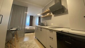 A modern kitchen with a built-in oven, a dishwasher, and a dining area with a table and chairs. - EM04- Studio premium - pat matrimonial (Târgu Jiu)