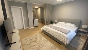 A modern bedroom with a large bed, a TV, and a desk. - EM04- Studio premium - pat matrimonial (Târgu Jiu)