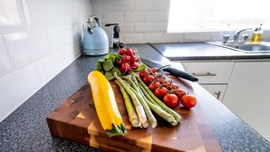 Un plan de travail de cuisine sur lequel on trouve une variété de légumes frais, notamment des asperges, des tomates et une courgette jaune.