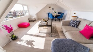 Un appartement moderne de style «loft», comprenant un coin repas, un canapé, une table basse et une vue sur la ville.