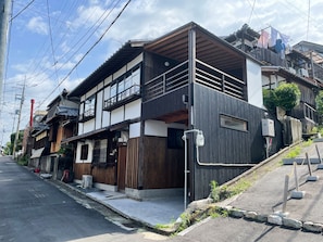 Une maison traditionnelle japonaise dotée d’une extension moderne, avec une façade en bois et un balcon.
