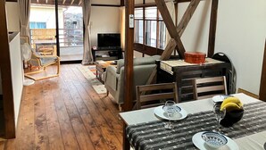 Une pièce chaleureuse avec un plancher en bois, une table à manger dressée avec des assiettes et un verre, une télévision et un canapé.