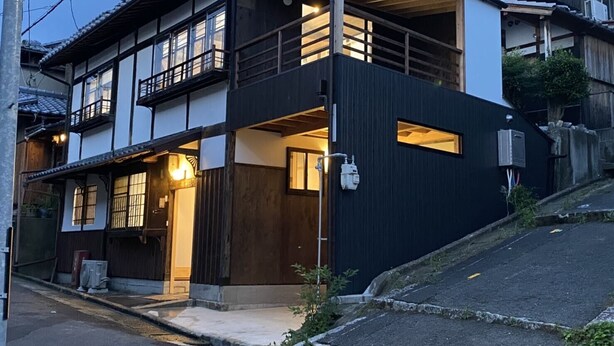 Une maison traditionnelle japonaise dotée d’une extension moderne, comprenant un balcon et une entrée en bois.