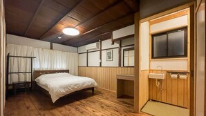 Une chambre avec un plancher en bois, un lit, un bureau et une fenêtre.