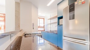 Eine moderne Küche mit einem Edelstahl-Kühlschrank, blauen Schränken und einer Arbeitsplatte aus Granit.