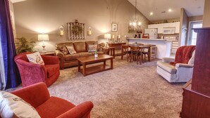 A living room with a sofa, armchairs, a coffee table, and a dining area with a table and chairs.