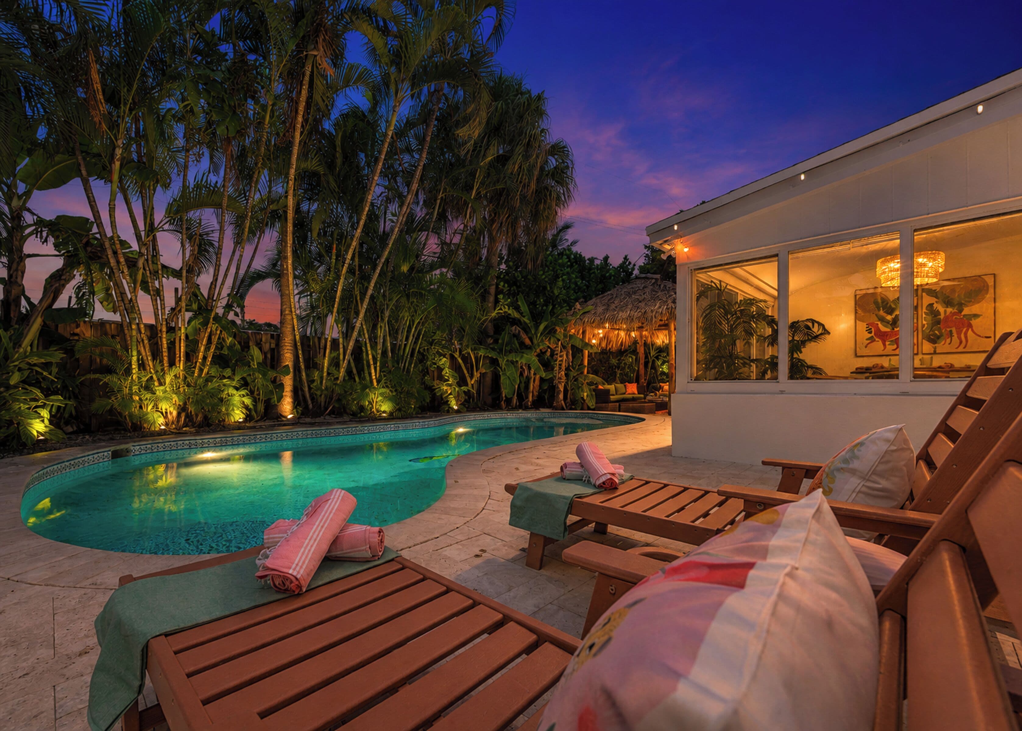 A pool area with lounge chairs and a thatched-roof structure.