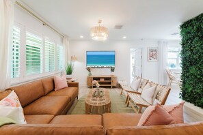 A living room with a sofa, chairs, a coffee table, and a TV.