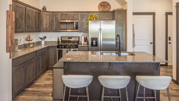 A modern kitchen with dark wood cabinets, stainless steel appliances, and a granite countertop. - Brand New Townhome - 10 Minutes from Downtown (Bozeman)