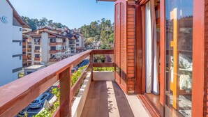 A balcony with a wooden railing overlooking a residential area with multiple buildings and parked cars. - Apartment in Gramado city center, 100m from Rua Coberta (Gramado)