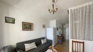 Un salon comprenant un canapé, une table basse, un lustre, un réfrigérateur et un fauteuil.