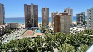 Un immeuble de grande hauteur doté d’un court de tennis et d’un espace piscine, offrant une vue sur la plage.