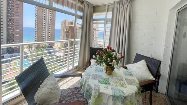 Un balcon avec une table, des chaises et un vase de fleurs.