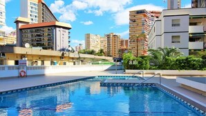 Une piscine à l’eau d’un bleu cristallin, entourée d’une plage et dotée d’une bouée de sauvetage.