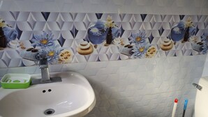 A bathroom with a sink, toilet, and decorative tiles.