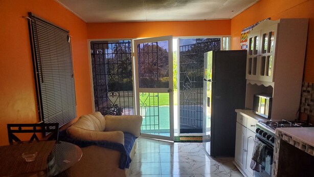 A compact living space with a sofa, dining table, and a kitchen area including a stove and refrigerator.