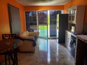 Un espace de vie compact comprenant un canapé, une table à manger et un coin cuisine équipé d’une cuisinière et d’un réfrigérateur.