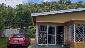 A red car parked in front of a building with a gated entrance, a paved driveway, and a green lawn.