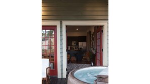 Eine Holzterrasse mit Whirlpool, Esstisch und Stühlen.