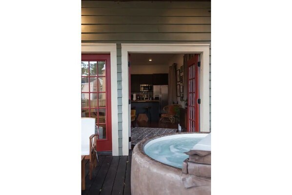 A wooden deck with a hot tub, a dining table, and chairs.