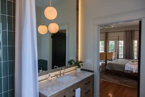 A modern bathroom with a large mirror, two pendant lights, and a sink.