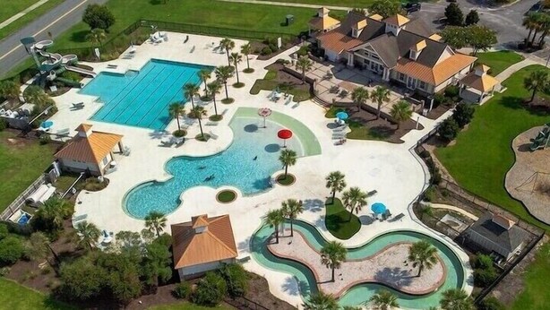 Vista aérea de una zona residencial con una gran piscina, varias toboganes de agua y un césped bien cuidado.