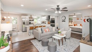 A modern living room with a grey sofa, a coffee table, and a dining area with a bar.