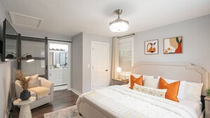 A bedroom with a large bed, a nightstand, a chair, and a mirror.
