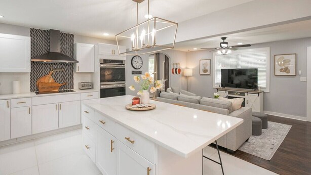 A modern kitchen with white cabinetry, a central island, and a built-in oven.