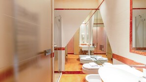 Ein modernes Badezimmer mit einer Duschkabine aus Glas, mehreren Toiletten und einem großzügigen Waschbecken.