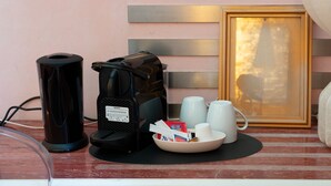 Eine Kaffeemaschine, eine Tasche und eine Schale mit Tassen und Taschentüchern auf einem Tisch.