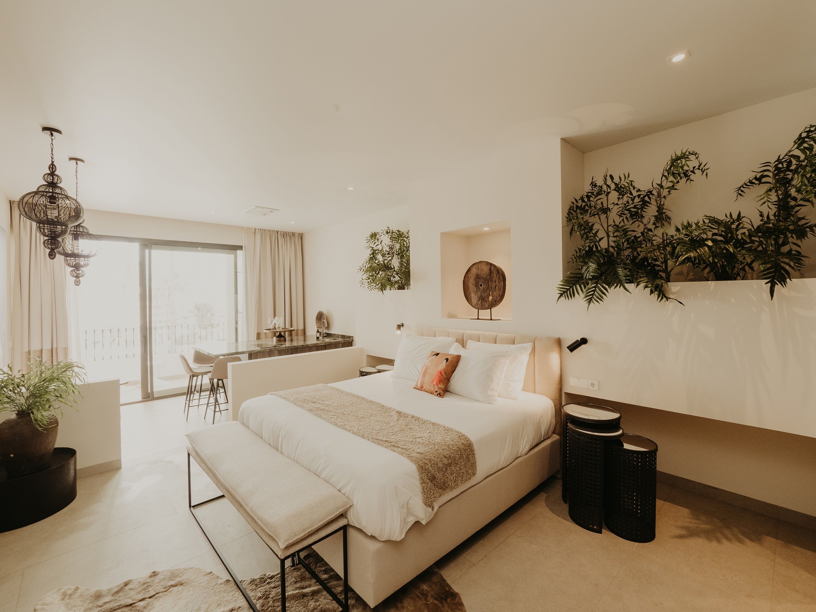 Une chambre moderne avec un grand lit, un banc, un bureau et un balcon.