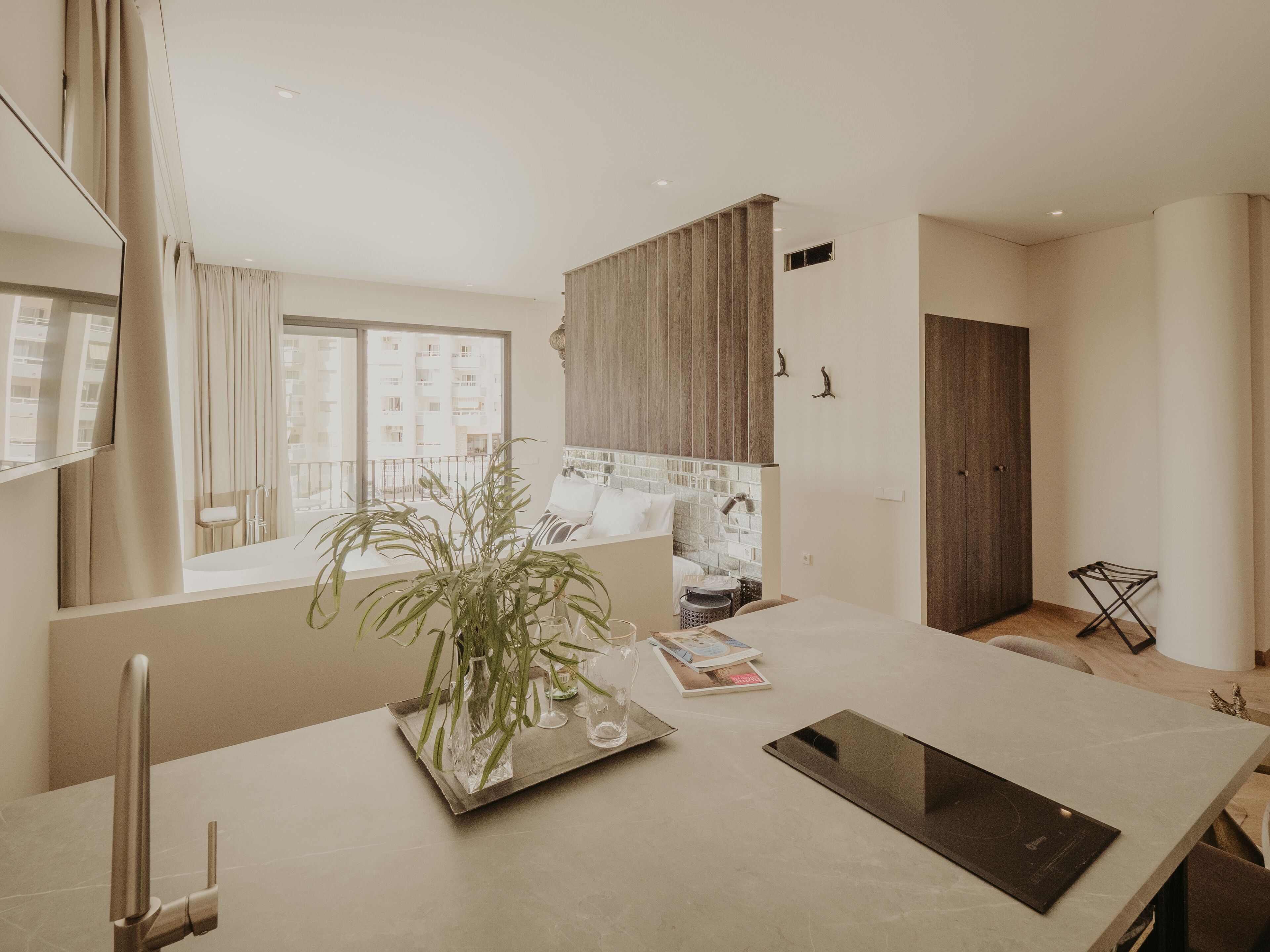 A modern kitchen with a large window, a plant on the counter, and a tablet.
