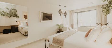 A modern bedroom with a large bed, a bedside table, a mirror, and a window.