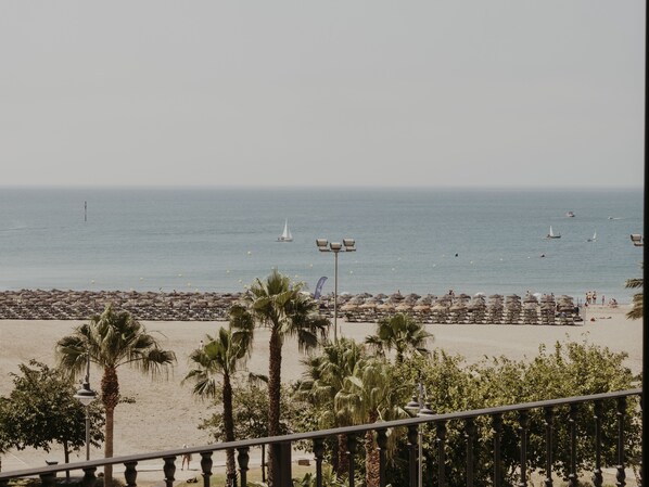 A beach with umbrellas and palm trees.