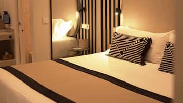 Una habitación de hotel con cama, mesita de noche y espejo.
