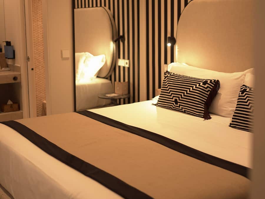 Una habitación de hotel con cama, mesita de noche y espejo.