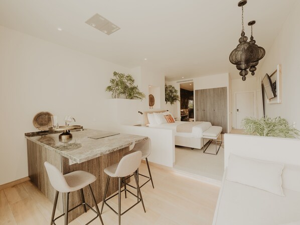 A modern kitchen with a central island, bar stools, and a dining area.